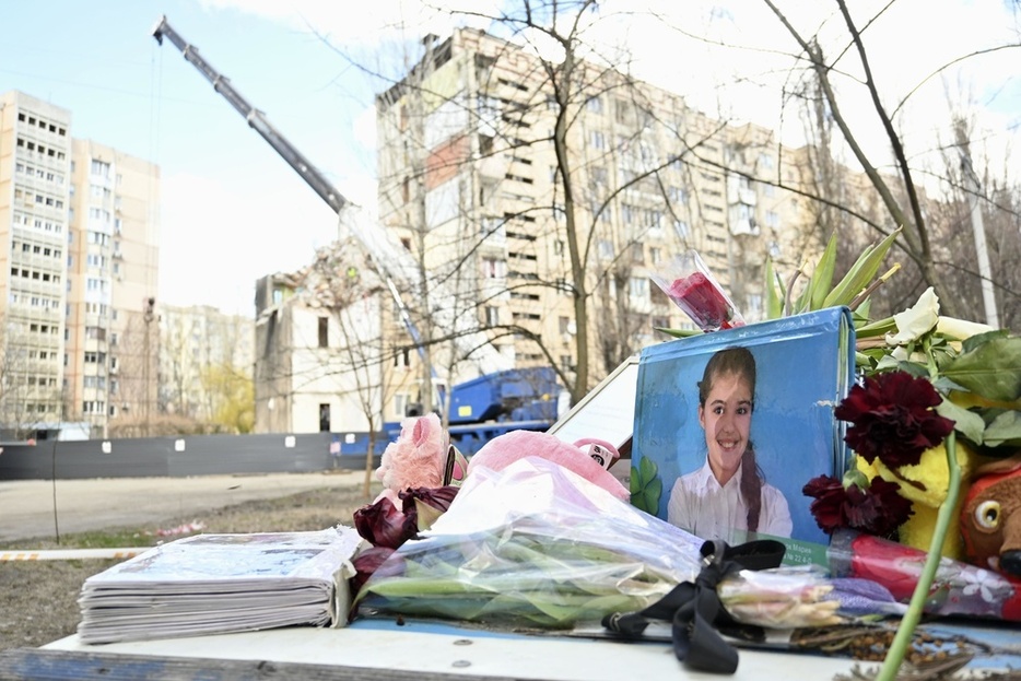 ロシアの無人機攻撃を受けたアパートの脇に、亡くなった子どもの写真や花が手向けられていた＝3月、ウクライナ・オデッサ（共同）