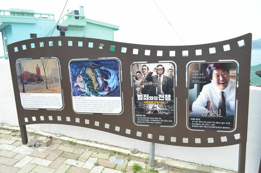 チェ・ミンシク主演映画『悪いやつら』とソン・ガンホ主演『弁護人』が釜山・影島のヒンヨウル文化村で撮影されたことを示すパネル