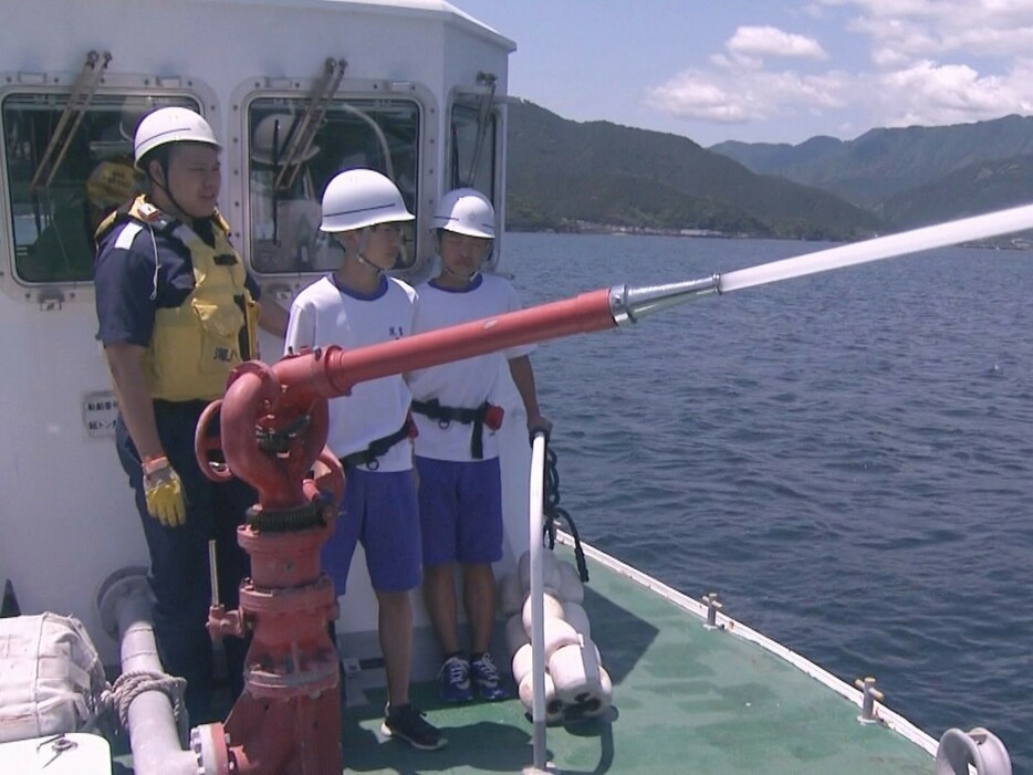 海上保安庁の巡視艇で放水銃を体験する中学生 三重県尾鷲市