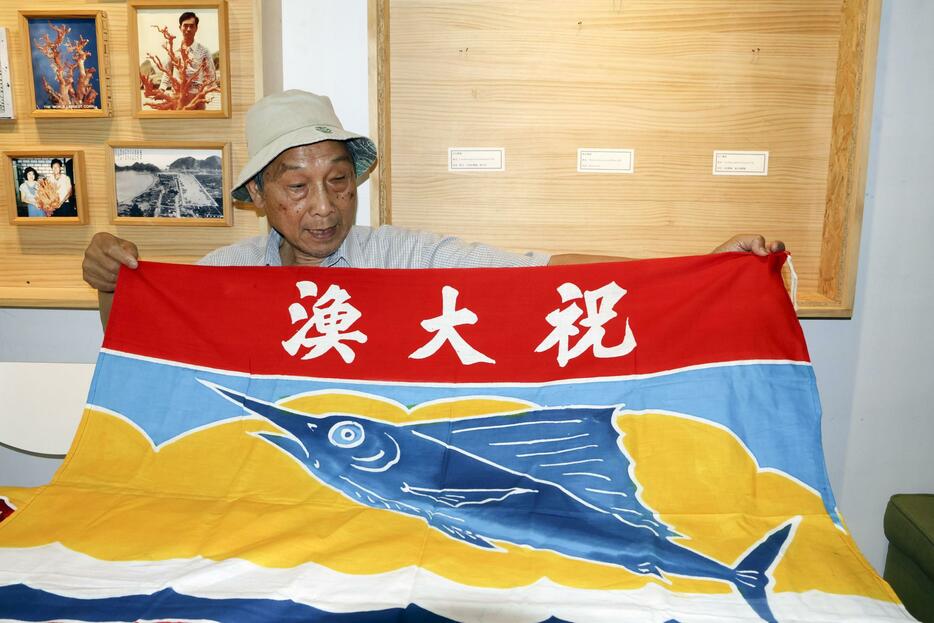 台湾北東部・宜蘭県蘇澳鎮で大漁旗について説明する頼栄興さん＝2024年5月10日（共同）