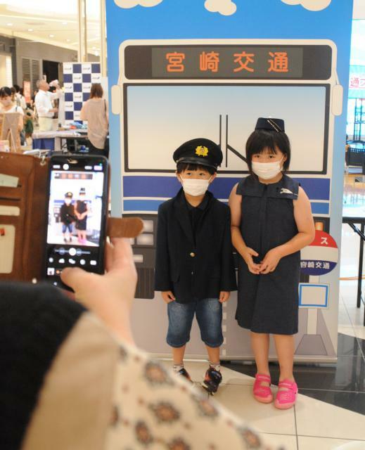 バス運転士などの制服を着て写真撮影する子どもたち＝２３日午後、宮崎市・イオンモール宮崎
