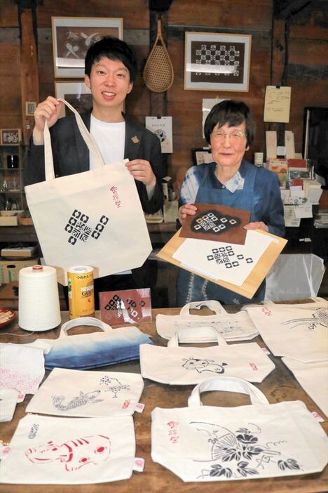 再生紙糸で織られた生地に会津型をあしらった製品を披露する滝井さん（左）と冠木さん