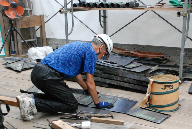 銅板の形を整える職人。一枚一枚に番号が付けられている＝笠間稲荷神社で2024年6月28日午前11時16分、鈴木敬子撮影