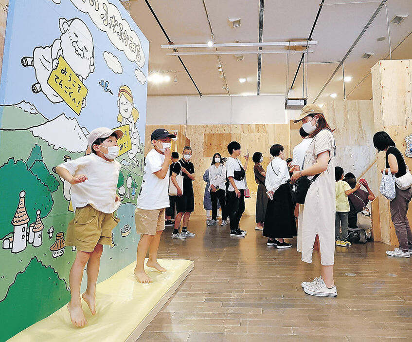 巨大パネルやゲームで絵本の世界を楽しむ親子連れ＝１５日午前１０時１５分、金沢２１世紀美術館