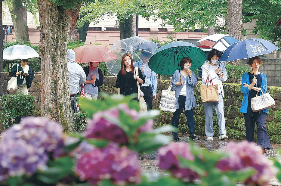 雨の中、薄手の上着などを羽織って行き交う人＝２８日午前８時４０分、金沢市広坂２丁目