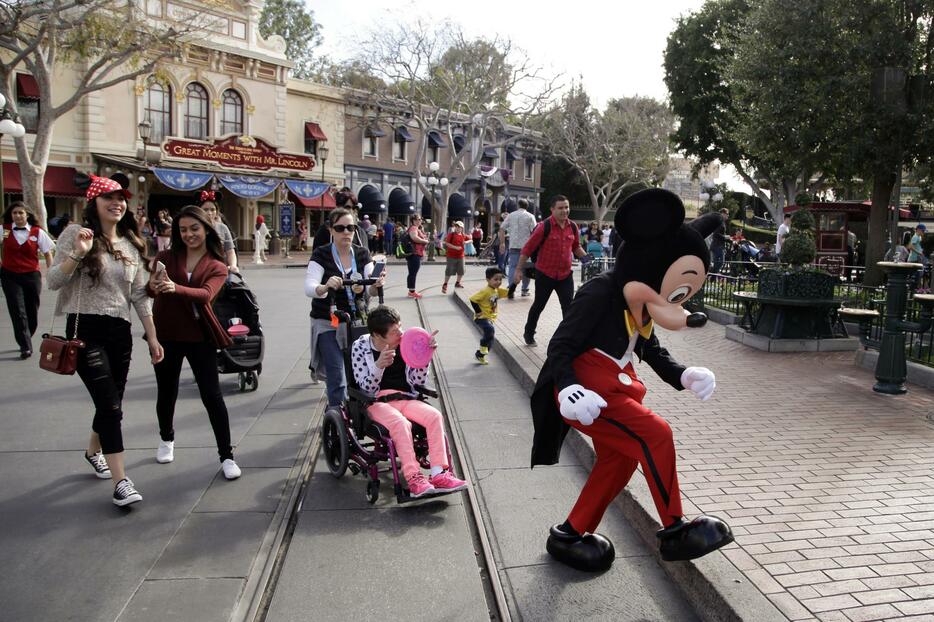 ディズニーランドで写真を撮るためミッキーマウスを追いかける人たち＝米カリフォルニア州アナハイム（AP＝共同）