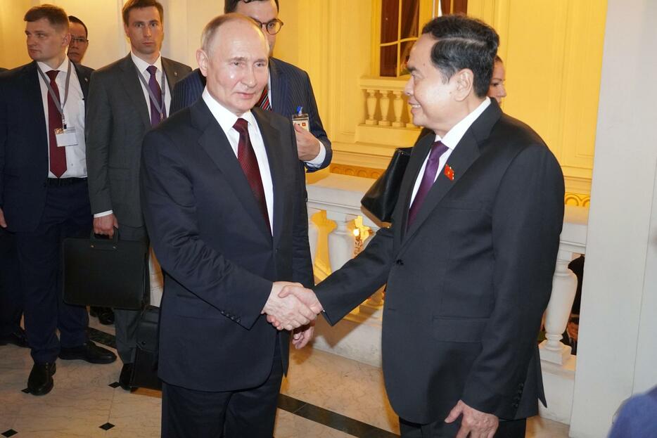 20日、ベトナム・ハノイでチャン・タイン・マン国会議長（右）と握手するロシアのプーチン大統領（共同）