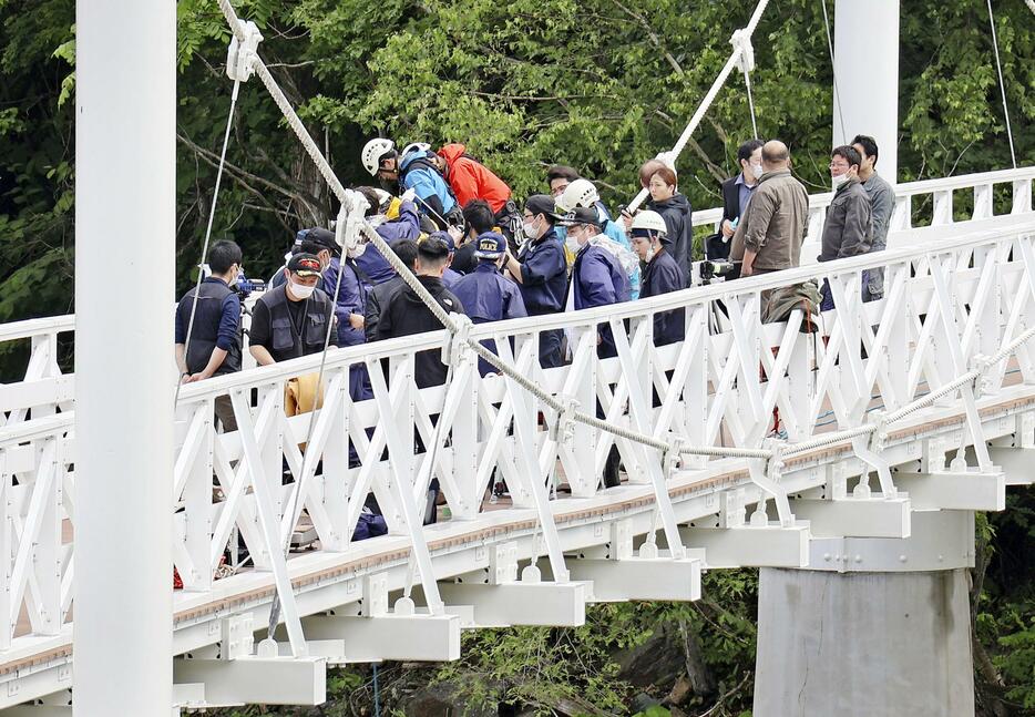 女子高校生がつり橋から川に落とされ殺害された事件の現場で実況見分する捜査員ら＝25日午前、北海道旭川市