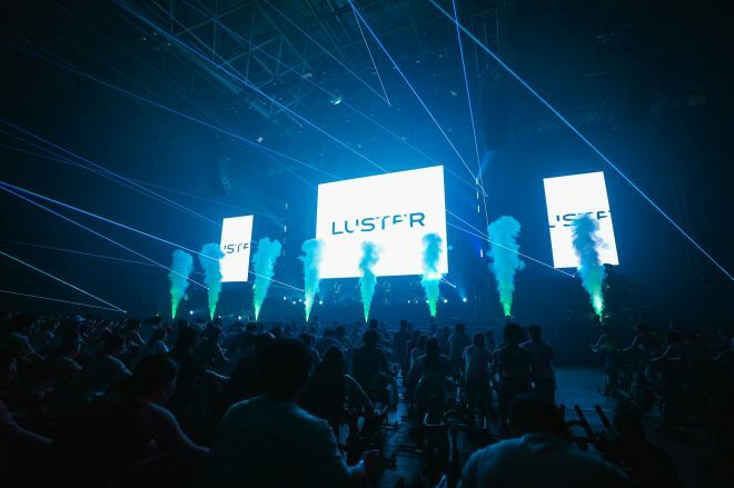 クラブやライブのような空間で音楽に合わせて運動する暗闇バイクフィットネスの大規模フェス「LUSTER」の様子＝画像提供：FEEL CONNECTION社
