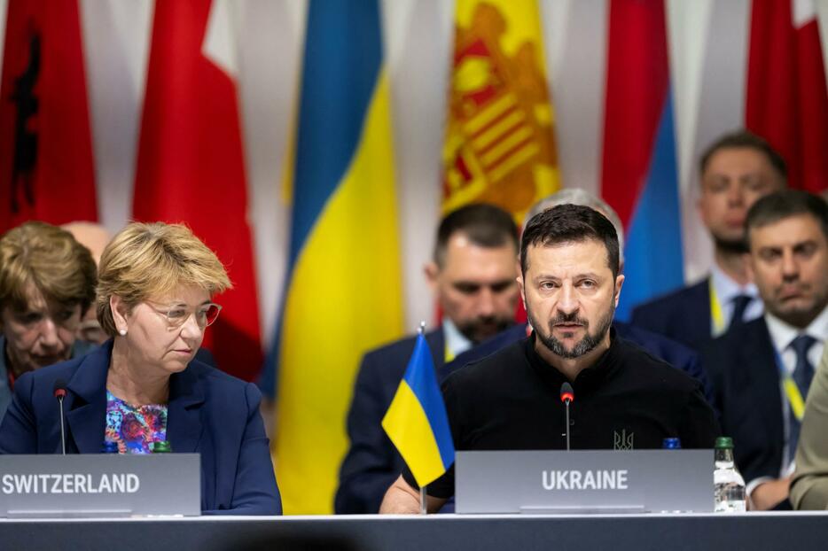 16日、スイスで開かれた「世界平和サミット」の全体会合で演説するウクライナのゼレンスキー大統領（右）（ロイター＝共同）