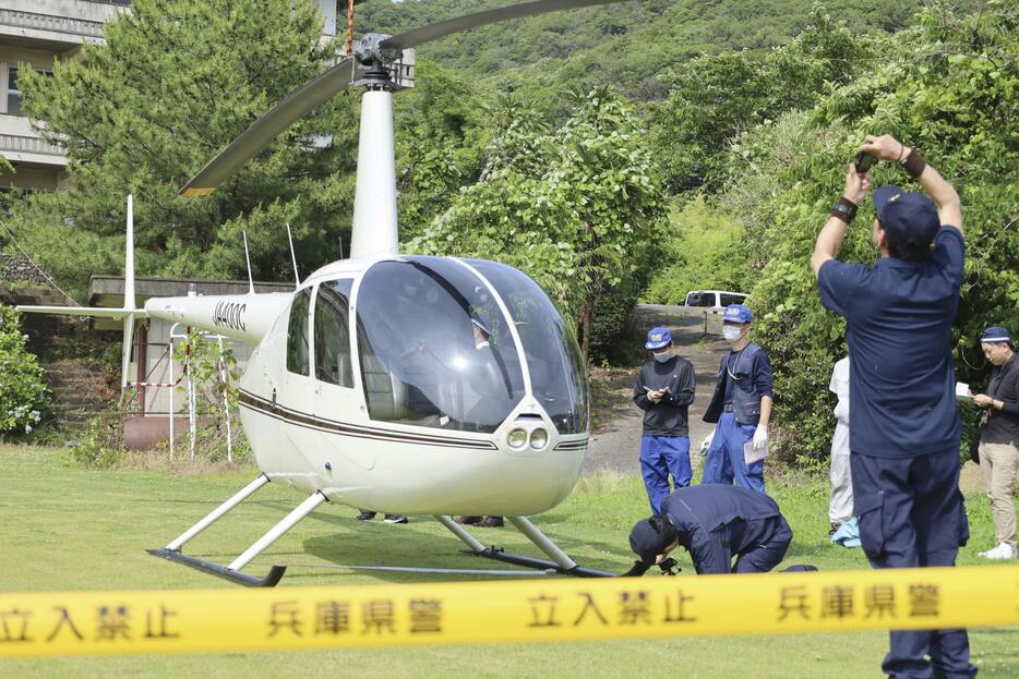 相生学院高のグラウンドに緊急着陸したヘリコプターを調べる航空事故調査官ら＝11日午後、兵庫県相生市