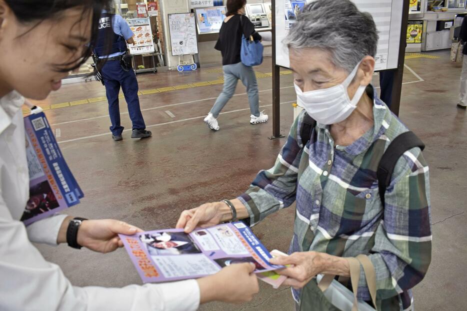 JR松阪駅で情報提供を呼びかけるチラシを受け取る女性＝13日午前、三重県松阪市