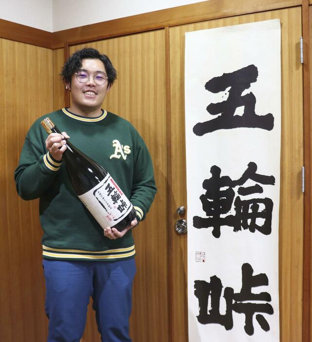 焼酎「五輪峠」の瓶を持つ斎藤柊斗さん＝2024年4月、新潟県三条市