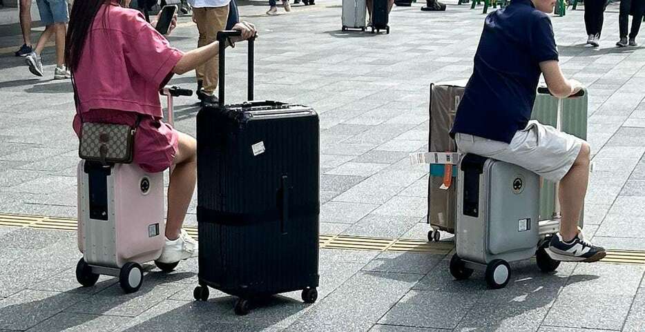 電動スーツケースに乗って移動する観光客