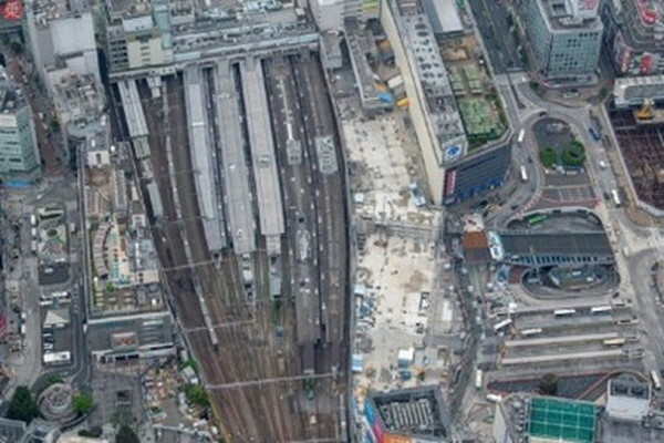 北側から見下ろすように撮影。JR埼京線のE233系電車が走り、山手線、総武線各駅停車、中央線、特急と、各ホームには電車が停車している。その右手には姿を消した小田急百貨店本館ビルの敷地（2024年5月8日、吉永陽一撮影）。