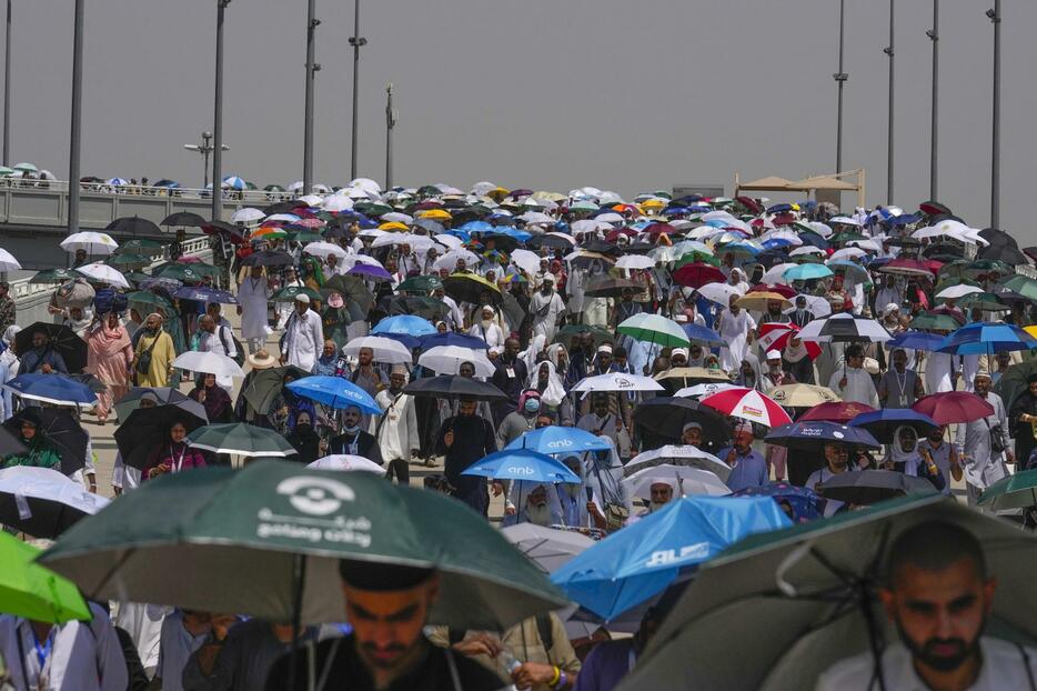 18日、サウジアラビア・メッカ近郊で日差しを避けるため傘を差す巡礼者ら（AP＝共同）