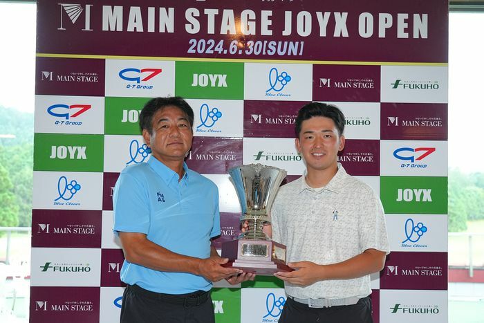 JOYX代表取締役社長の前村直昭氏（左）とカップを掲げる金子駆大（大会提供）