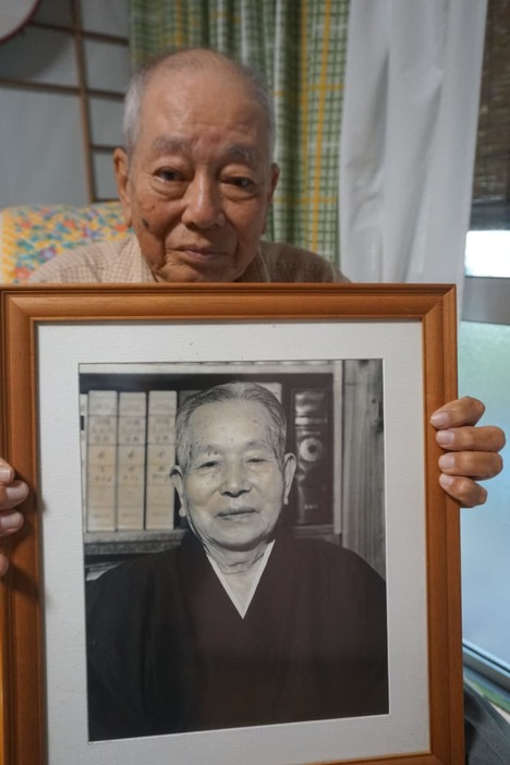 故牧野清さんの写真を手にする長男の光博さん＝２０２３年６月、沖縄県石垣市 (1)