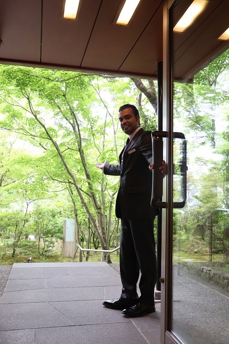 ロビーのドアを開けて離れへ通じる日本庭園を案内するジャヤスリヤさん＝雲仙市、半水盧