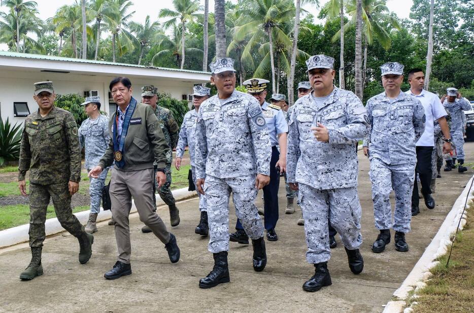 23日、フィリピン・パラワン島プエルトプリンセサの軍基地で、将兵らと歩くマルコス大統領（前列左から2人目）（共同）