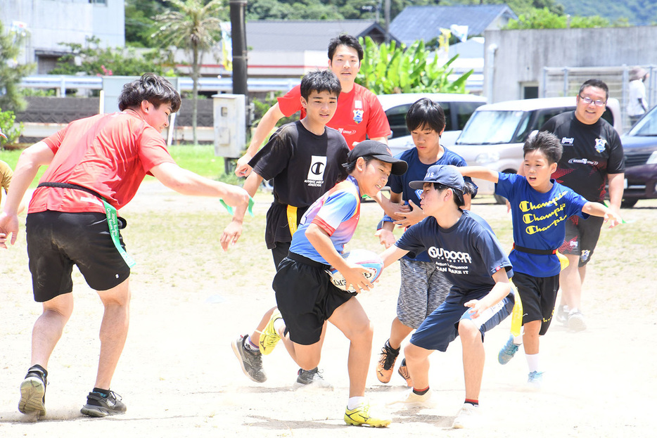 ラグビー選手とタグラグビーを楽しむ子どもたち＝29日、鹿児島県大和村の大和小学校グラウンド