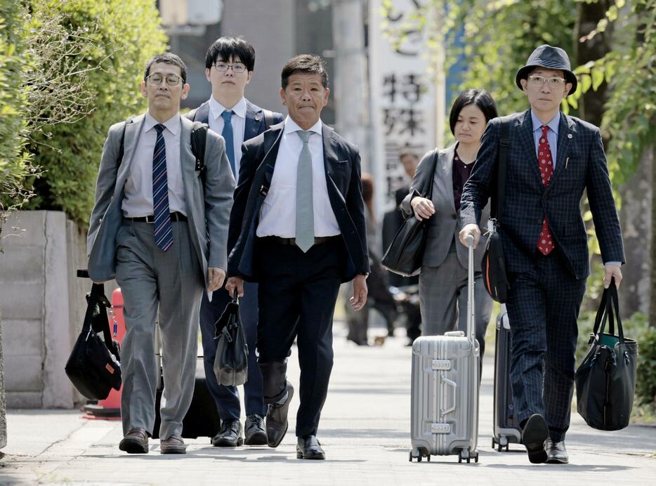 大阪地裁に向かうプレサンスコーポレーションの山岸忍元社長（中央）ら＝11日午前9時31分