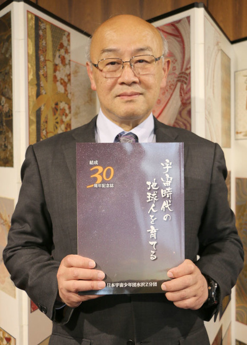 日本宇宙少年団水沢Z分団の結成30周年記念誌を手にする亀谷分団長