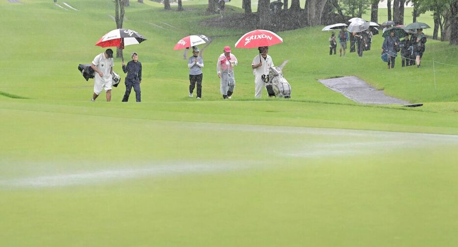 降雨で競技が中断となり水の浮いた１６番グリーンを引き揚げる選手たち（カメラ・今西　淳）