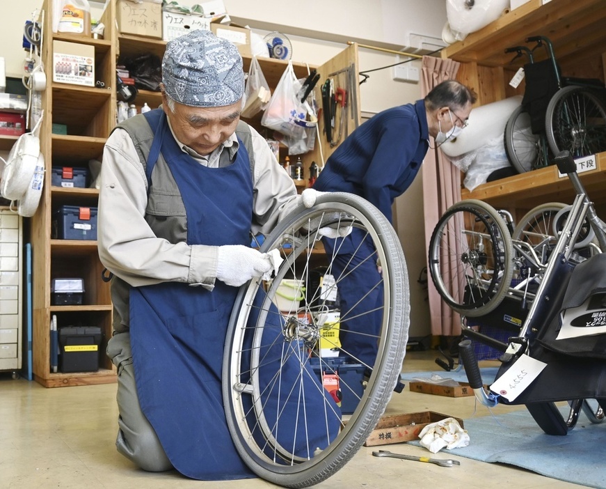 NPO法人「飛んでけ！車いす」の会の事務所で車いすを整備する男性＝4月、札幌市