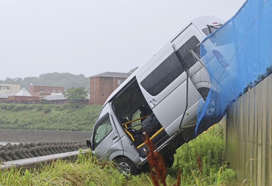 フェンスを突き破り転落した障害者施設の送迎車＝20日午後3時ごろ、熊本県苓北町