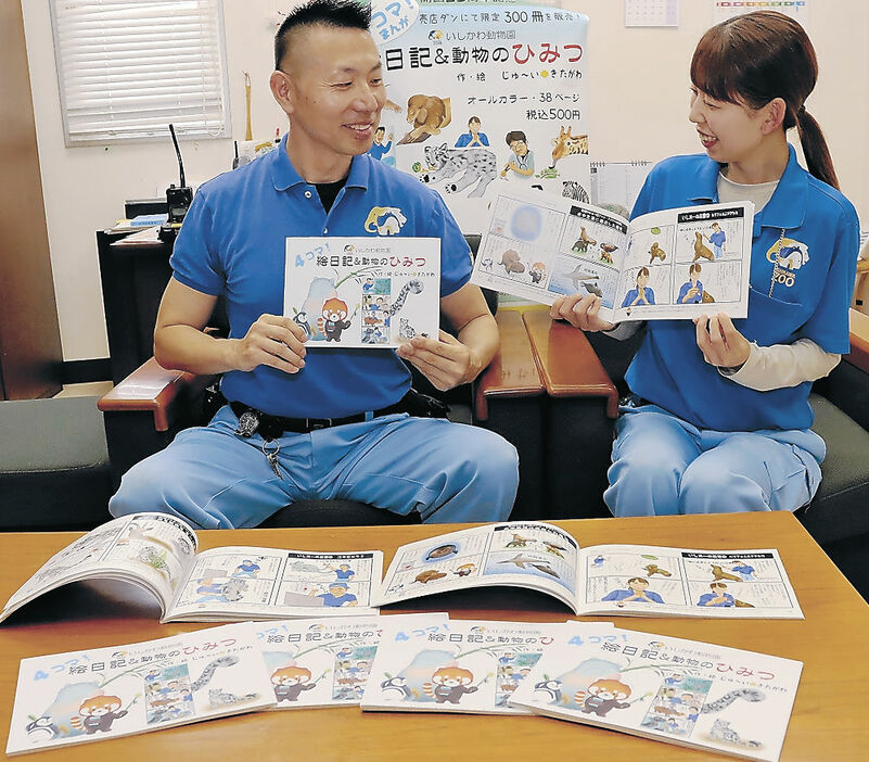飼育活動をつづった四コマ漫画本を紹介する北川獣医師（左）＝能美市のいしかわ動物園