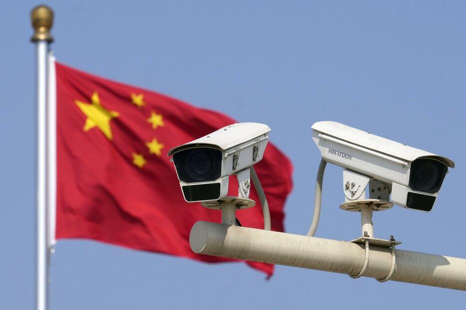 北京市内に設置された監視カメラ（手前）と掲げられた中国国旗＝3月（共同）