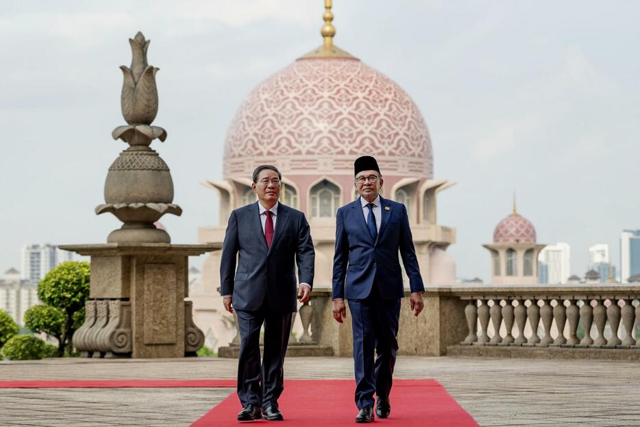 19日、マレーシアの行政都市プトラジャヤで首脳会談に臨むマレーシアのアンワル首相（右）と中国の李強首相（マレーシア政府提供・共同）