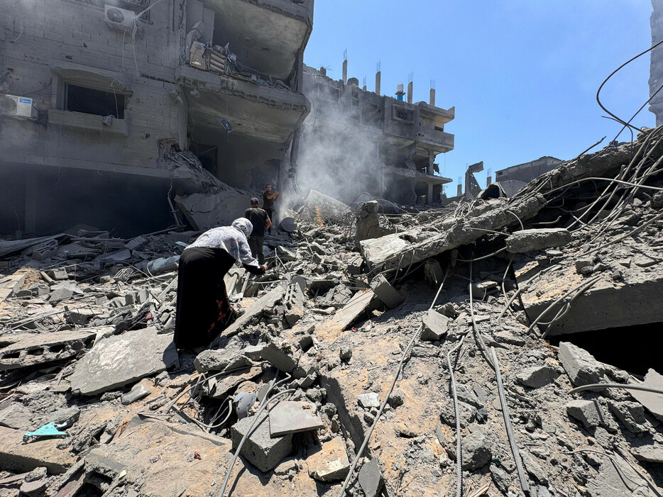 ２２日、パレスチナ自治区ガザ北部のガザ市で、イスラエルの空爆を受けた建物で救助に当たる住民。