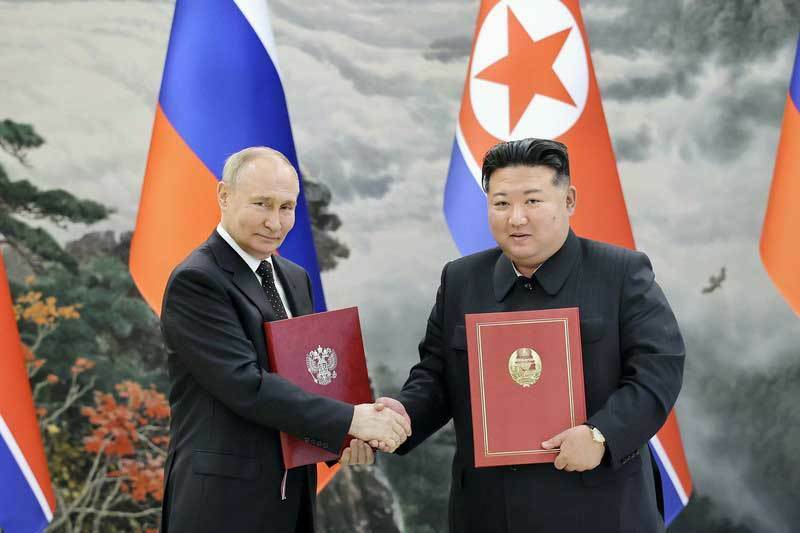 包括的戦略パートナーシップ条約に署名し握手するロシアのプーチン大統領（左）と北朝鮮の金正恩総書記＝6月19日、平壌（朝鮮中央通信＝共同）