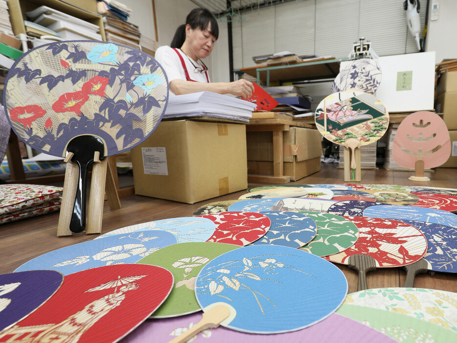 夏本番を前に、伝統工芸品「京うちわ」の生産が最盛期を迎えている。うちわ面と柄を別に作り、後から柄を差し込む構造が特徴。京都市山科区の塩見団扇ではさまざまな絵柄の京うちわが組み立てられていた＝１９日