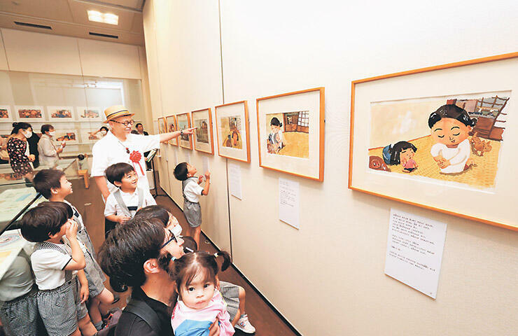 「しげちゃん」の原画が並ぶ一角。開会式後、帽子をかぶった長谷川さんが子どもたちと見て回った=高志の国文学館