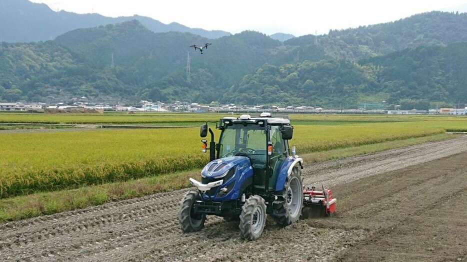 農地を走る無人走行のトラクターとドローン（愛媛県西条市提供）