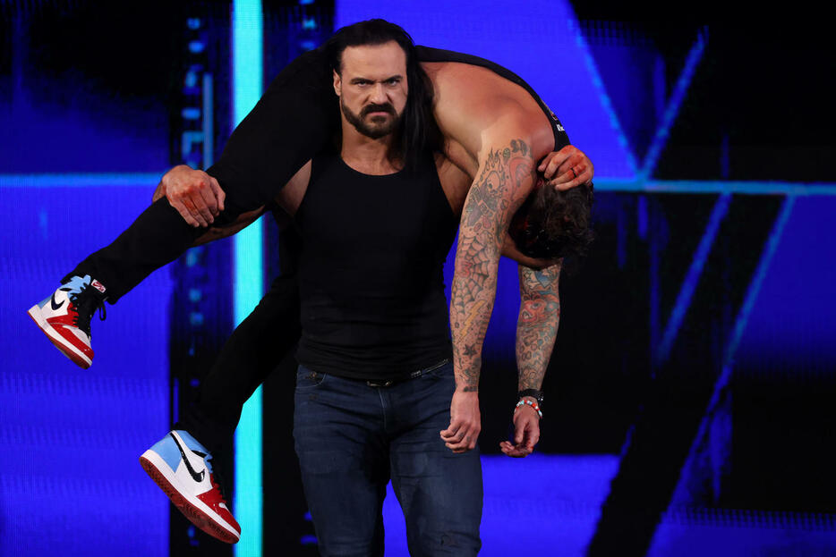 CMパンク（上）を襲撃し、担ぎ上げるドリュー・マッキンタイア（C）WWE