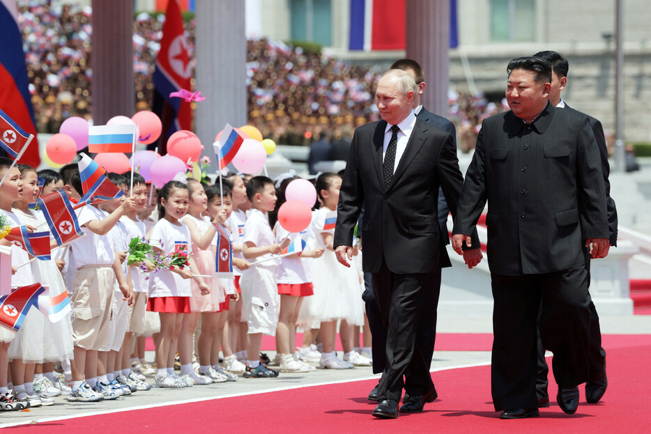 １９日、平壌の金日成広場で子供たちの歓迎を受けるロシアのプーチン大統領（左）と北朝鮮の金正恩朝鮮労働党総書記。
