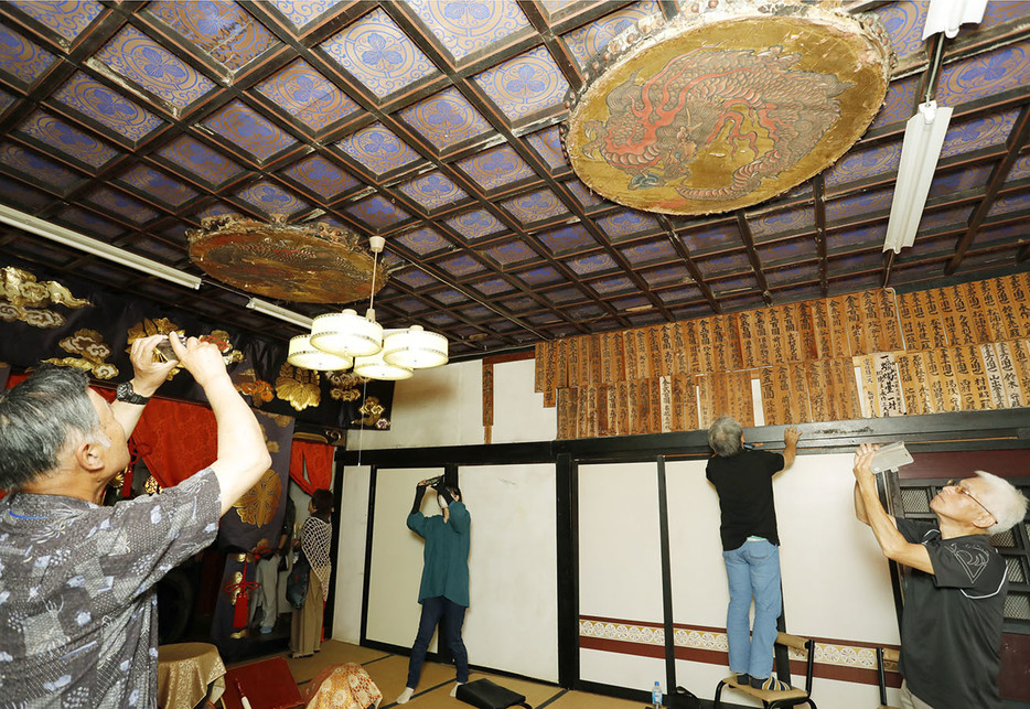 天井にはめこまれた直径約1.2㍍の龍の絵の太鼓面を撮影などする参加者ら＝上川町の長松寺で