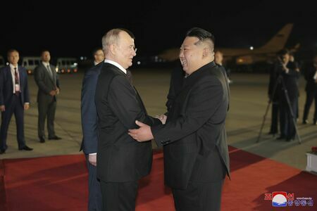 平壌国際空港にようやく到着したロシアのプーチン大統領（左）を笑顔で出迎える北朝鮮の金正恩朝鮮労働党総書記（写真：朝鮮通信＝共同）