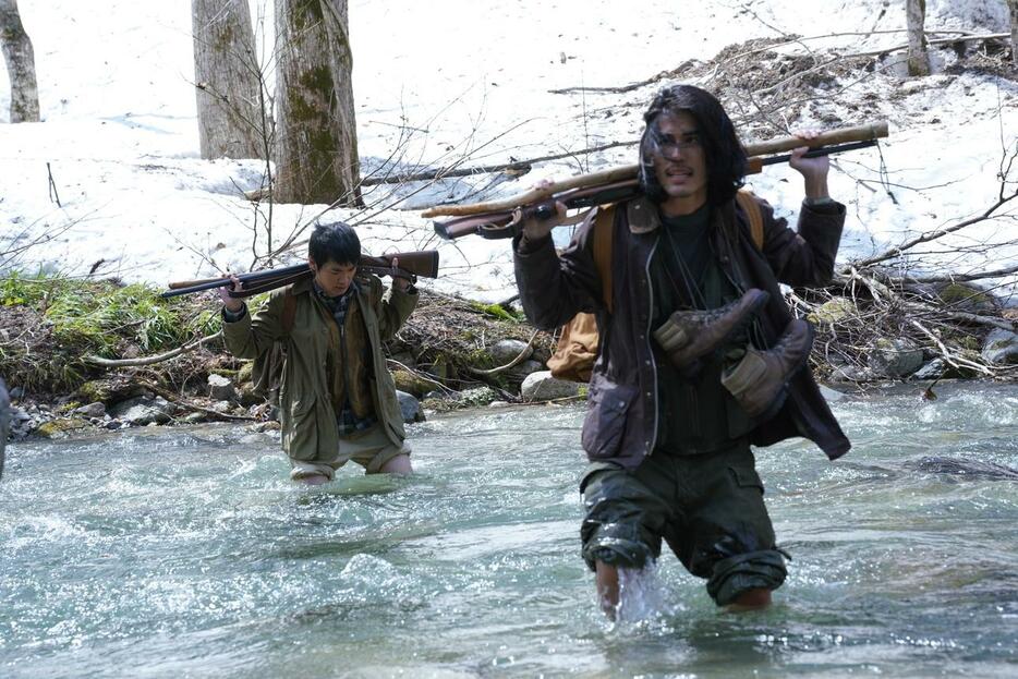 鉄砲を担ぎ冷たい川を渡る礼二郎と信行（杉田雷麟）　©飯嶋和一/小学館/FANTASIA