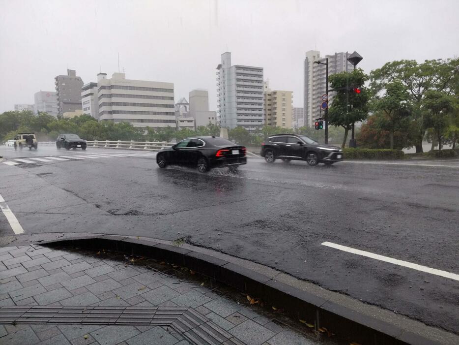 水しぶきを上げて走る車（23日午前、広島市中区の平和大通り）