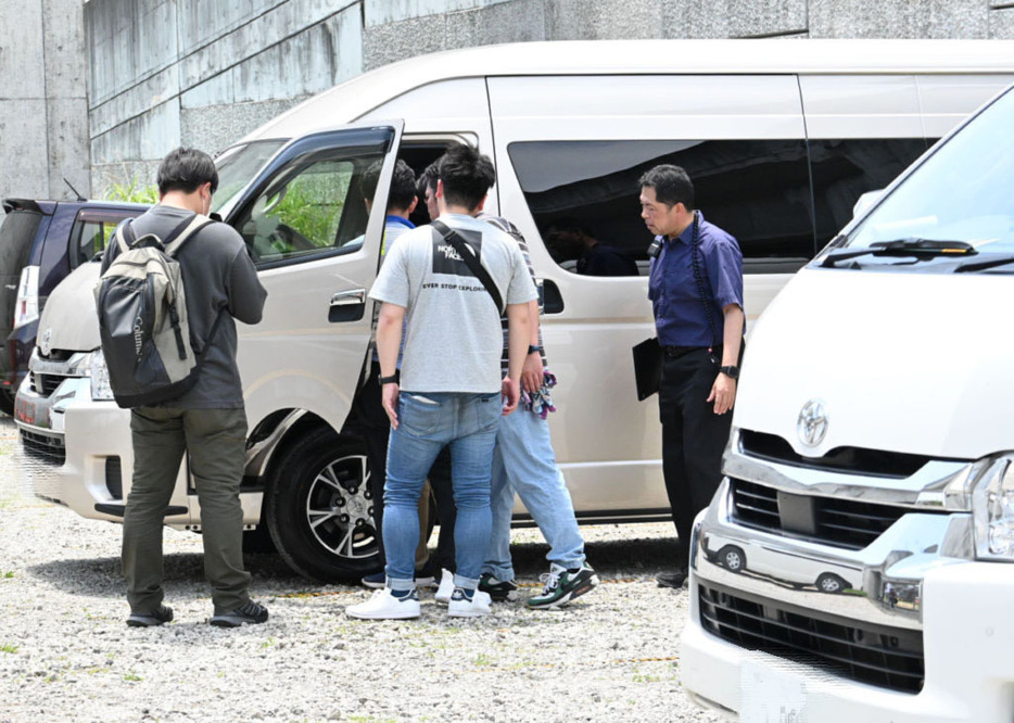 運転手を現行犯逮捕し、白タクに使われた車両を調べる静岡県警の捜査員ら＝25日午前、富士市の「富士山夢の大橋」訪問者用駐車場（写真を一部加工しています）