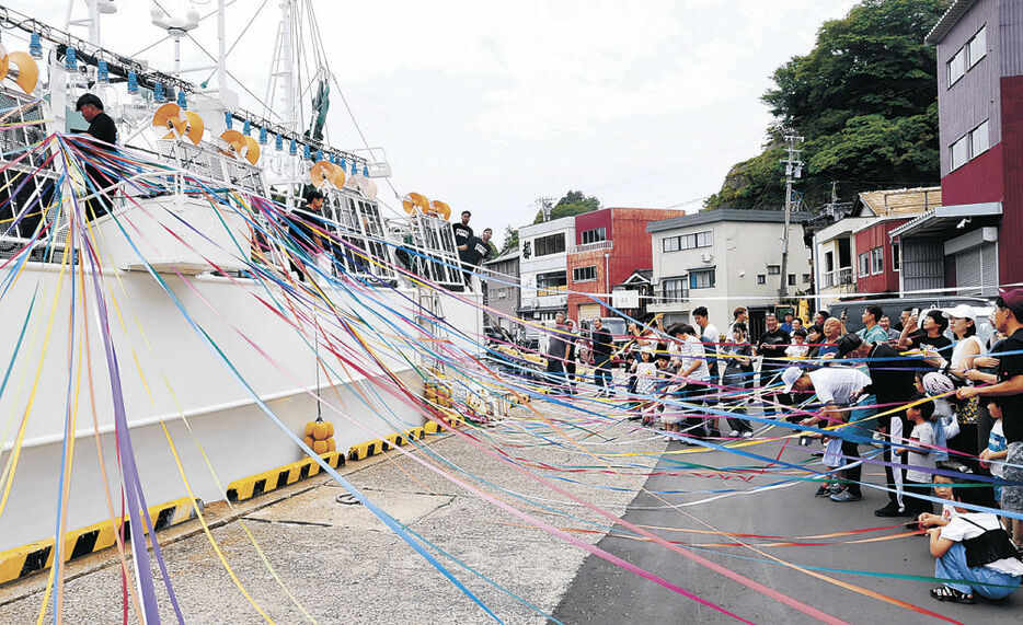 家族らの見送りを受けて出漁する中型イカ釣り船＝９日午前１１時、能登町小木港