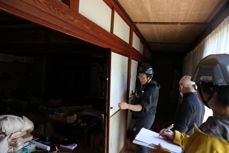 被災した住宅の柱の傾きを調べる山本周さん（奥）＝５月１１日、石川県輪島市