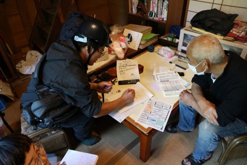 住人に説明する山本周さん（左）＝５月１１日、石川県輪島市