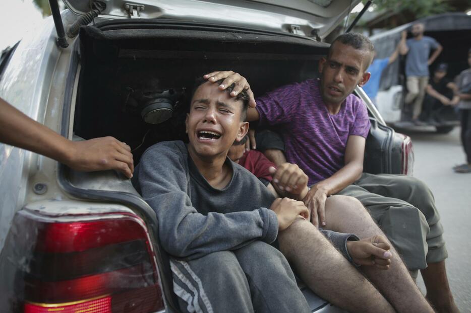 24日、パレスチナ自治区ガザ南部ハンユニスで、イスラエル軍の空爆で親族を亡くし、泣く住民（AP＝共同）