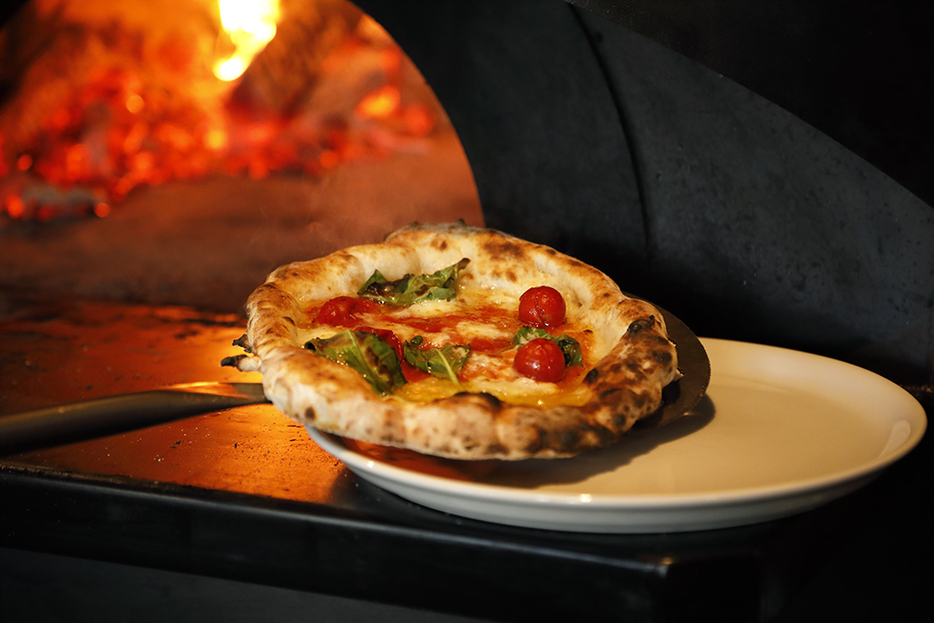 薪窯の高温で焼き上げられたピザ。香ばしい香りやとろりと溶けたチーズがたまらない